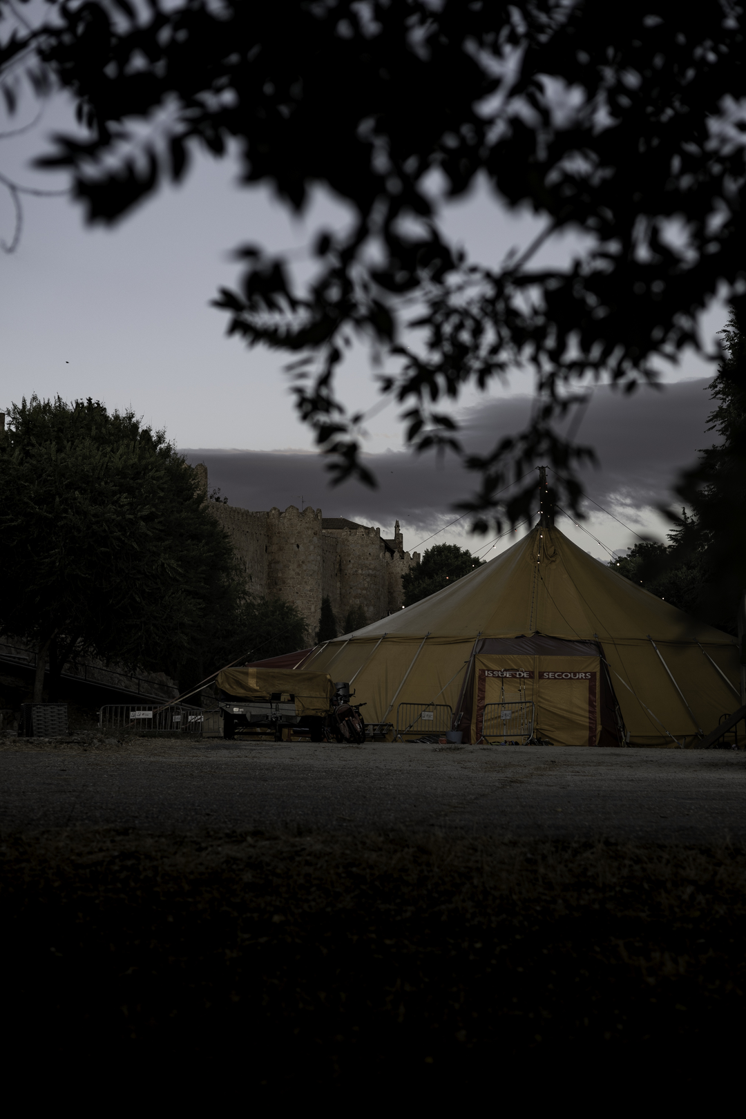   Evening view of a large yellow circus tent set up for the XIII International Circus Festival of Castilla y Leon, at Ávila, Spain, with the historic medieval walls of the city visible in the distance. Organized by Junta de Castilla y Leon. (c) pmartinasi