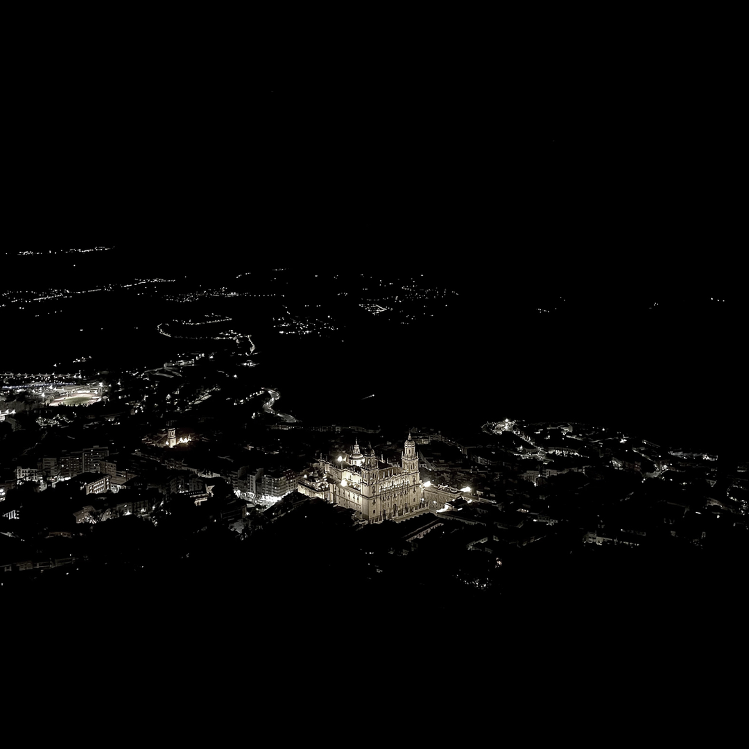  A breathtaking aerial night view of Jaén, Spain, featuring the illuminated Jaén Cathedral standing out against the surrounding dark cityscape. The historic architecture glows under the night sky, creating a striking contrast. (c) pmartinasi