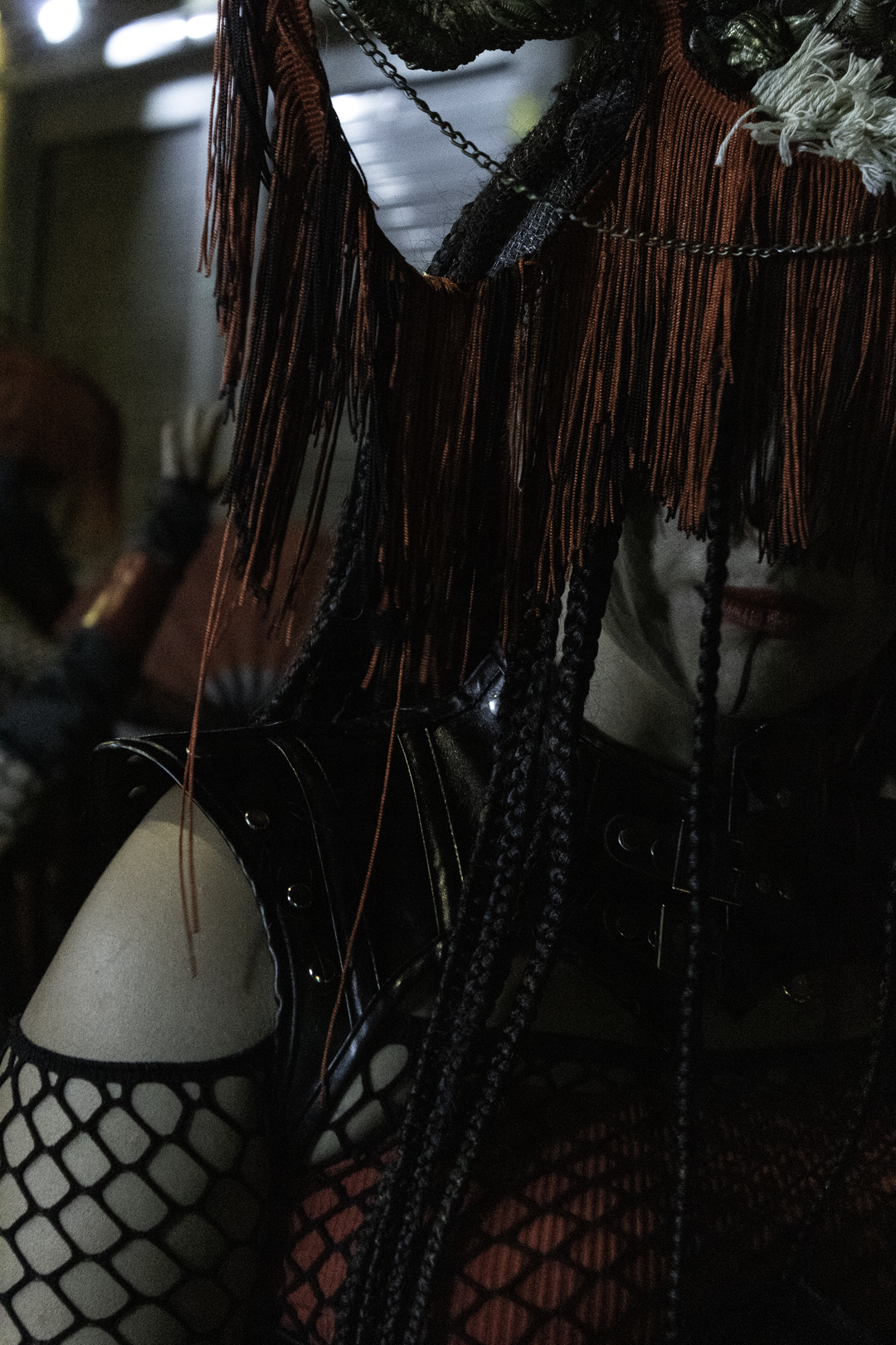  A close-up of a woman in red Asian-inspired costume with braids, fringe mask, and fishnet sleeves, captured while parading at the Medieval Fair and Market of Ávila, Spain. September 2025. (c) pmartinasi