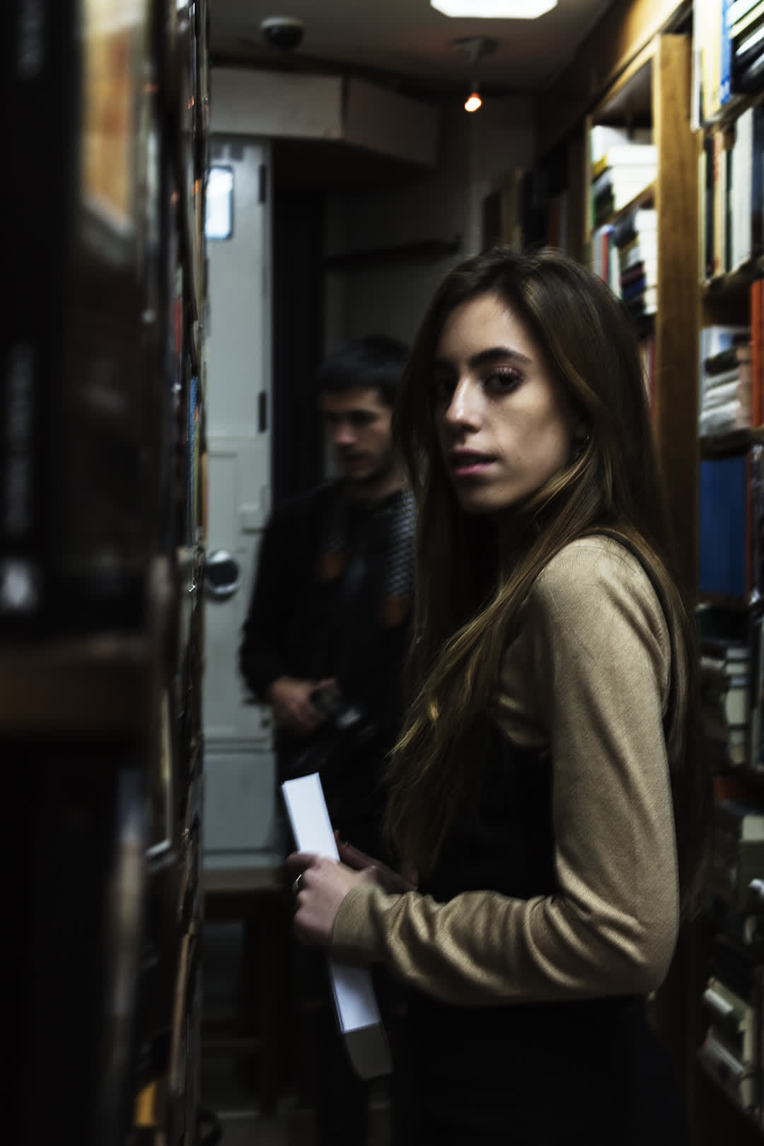 Young Woman Browsing Bookshelves in a Cozy Bookshop. (c) pmartinasi