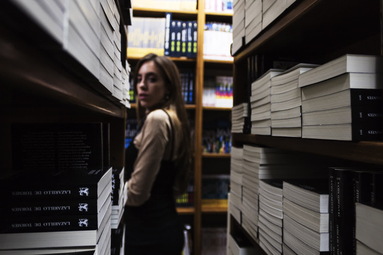 Young Woman Browsing Bookshelves in a Cozy Bookshop. (c) pmartinasi
