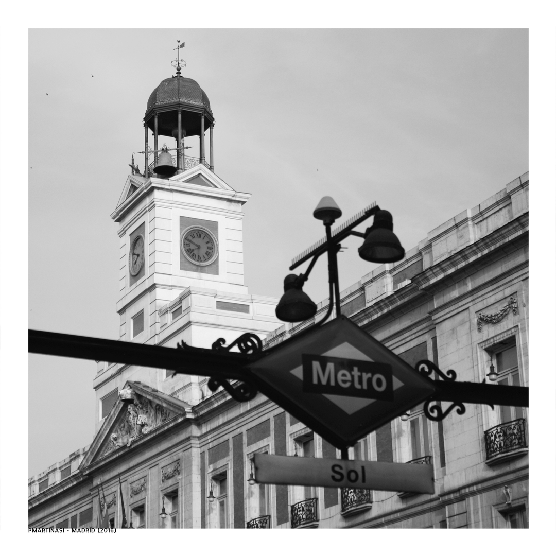  Classic black and white photo of the iconic Puerta del Sol Metro sign with the historic clock tower behind, capturing the spirit of central Madrid and its architectural charm. (c) pmartinasi