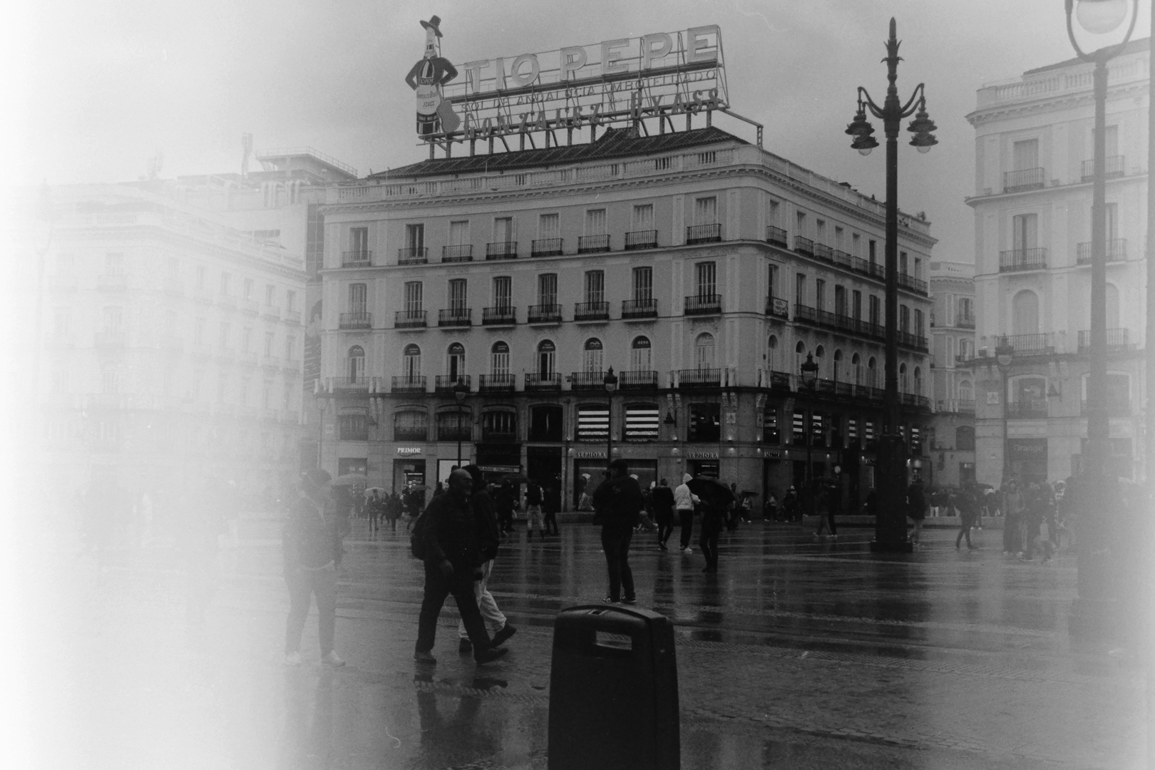 Rainy Day at Puerta del Sol with Iconic Tío Pepe Sign and Historic Architecture in Central Madrid (c) pmartinasi