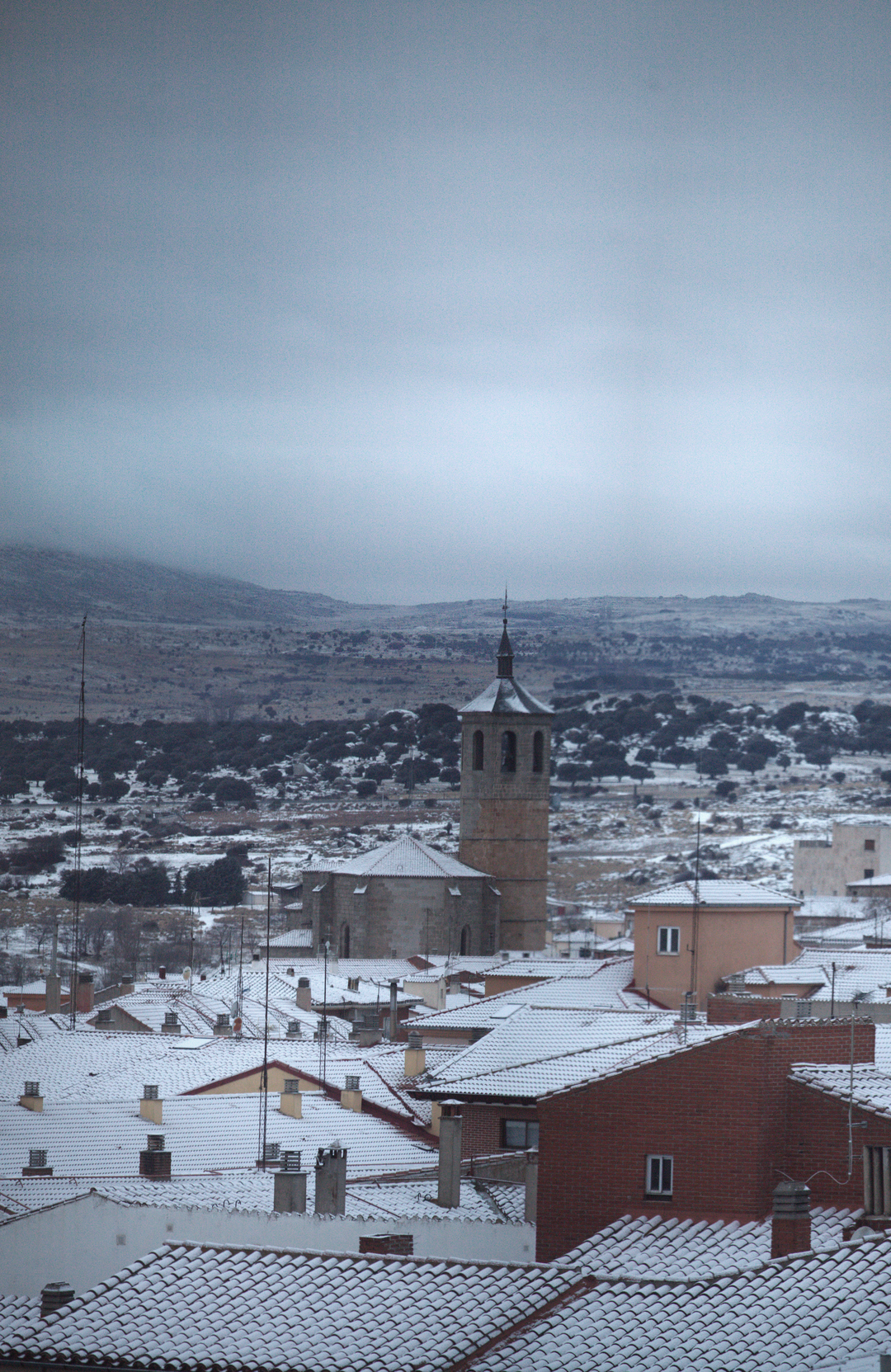  Panoramic winter view of Ávila from the south west, showing snow-covered rooftops, historic church towers and residential buildings, capturing the calm atmosphere of a cold day in a traditional Spanish city. January 2026. (c) pmartinasi