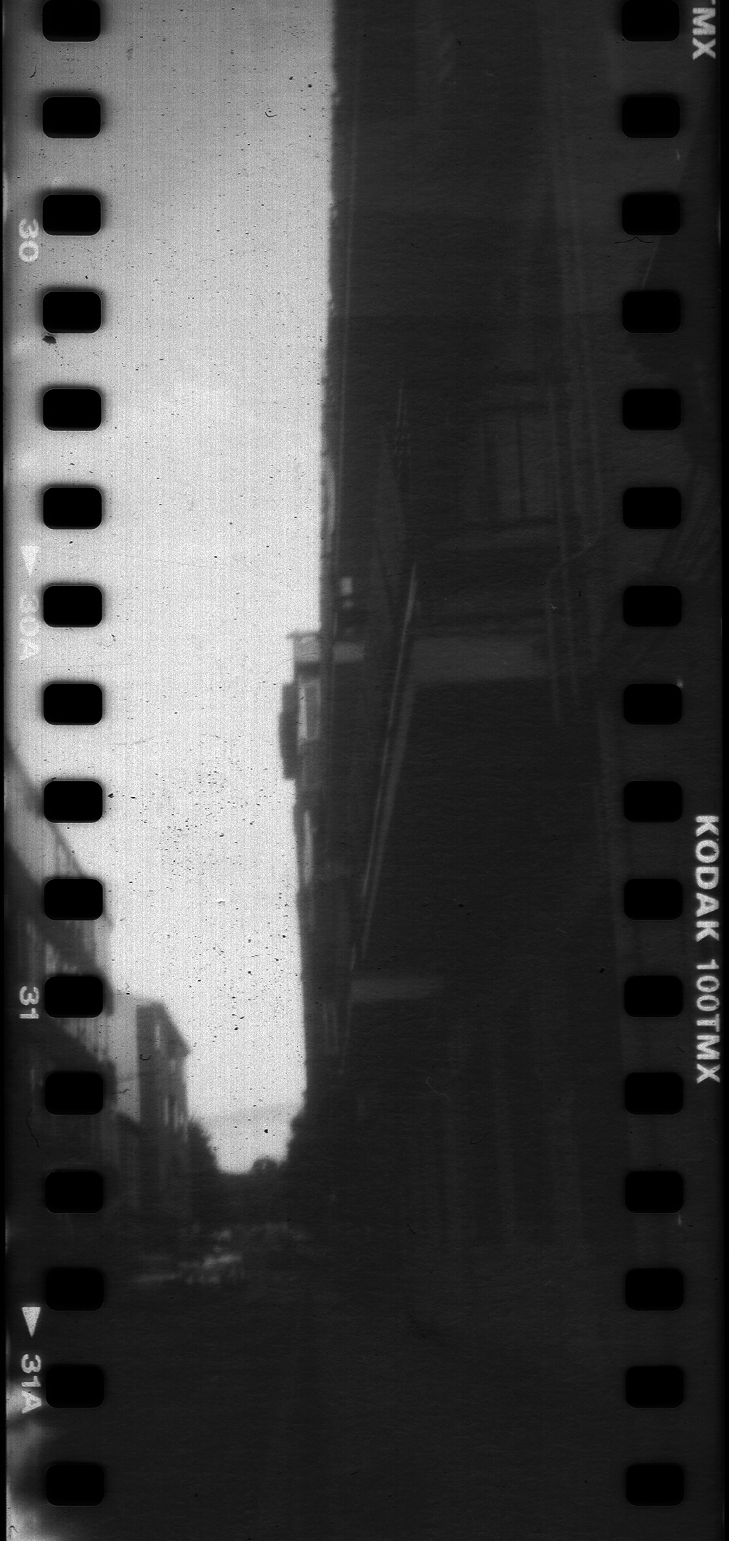  Analog black and white street photography of an urban scene in Avila, captured on Kodak 100TMX film reel. Featuring street lamps and buildings, this vintage film aesthetic evokes nostalgia and timeless urban imagery (c) pmartinasi