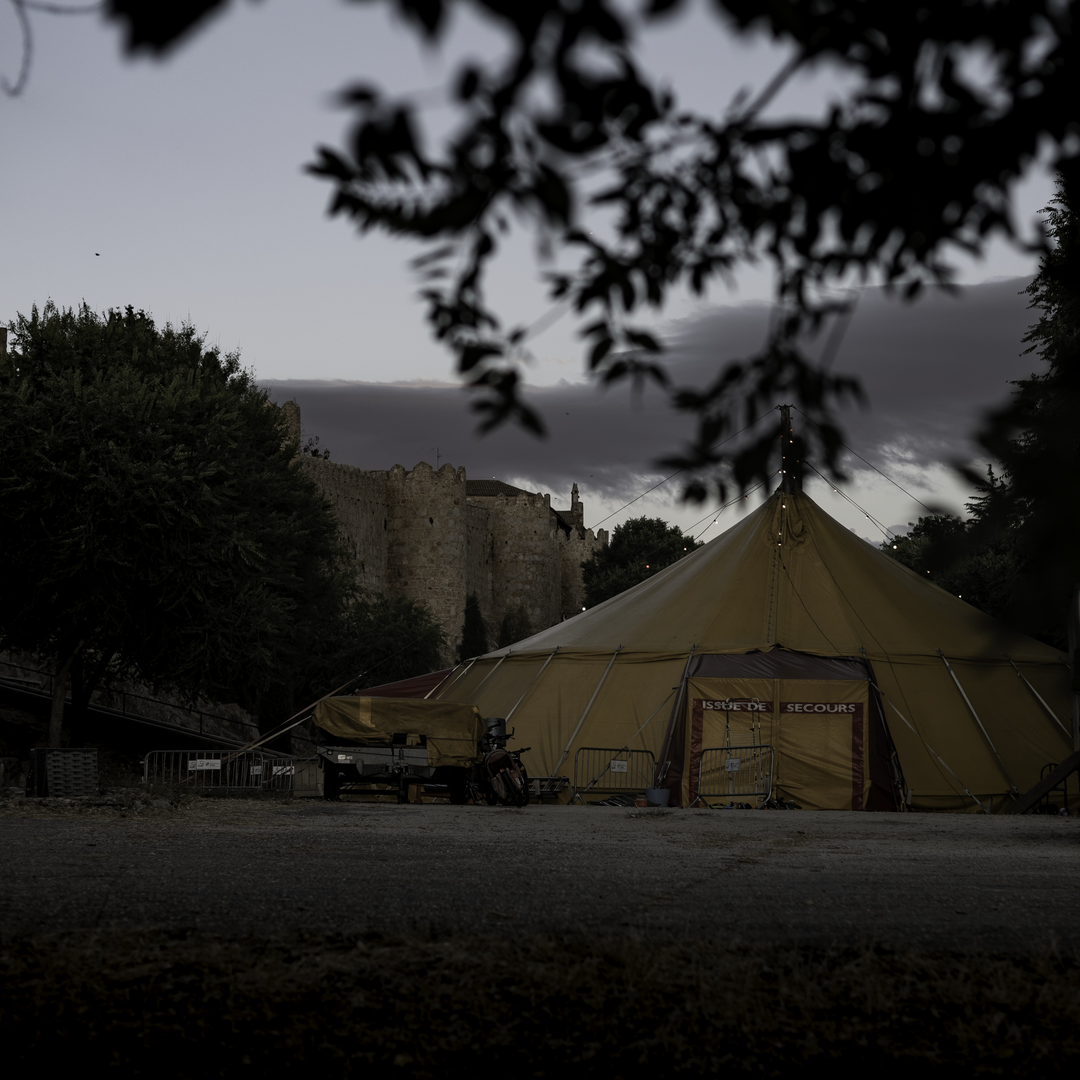   Evening view of a large yellow circus tent set up for the XIII International Circus Festival of Castilla y Leon, at Ávila, Spain, with the historic medieval walls of the city visible in the distance. Organized by Junta de Castilla y Leon. (c) pmartinasi