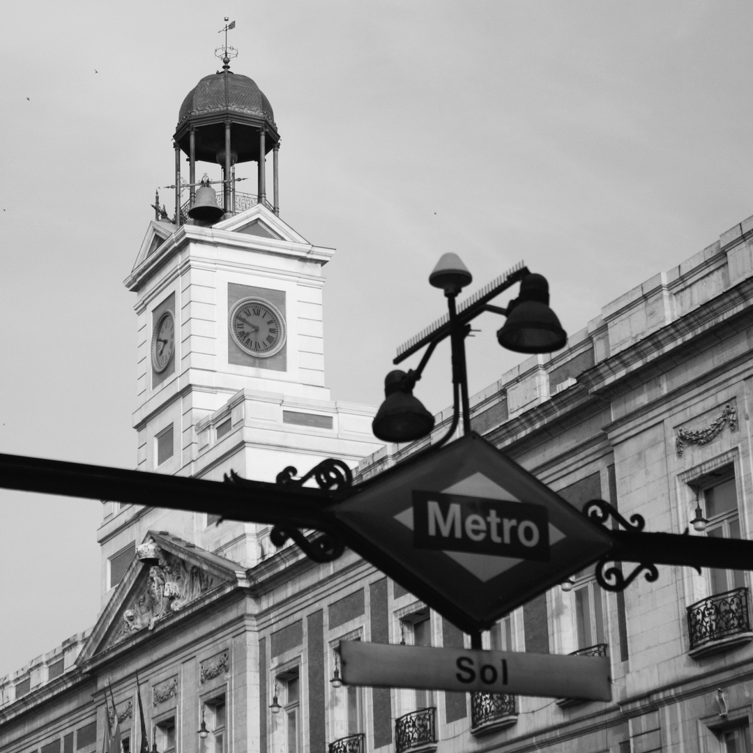  Classic black and white photo of the iconic Puerta del Sol Metro sign with the historic clock tower behind, capturing the spirit of central Madrid and its architectural charm. (c) pmartinasi