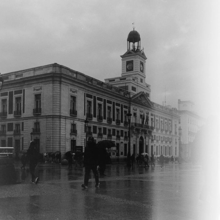 Moody Black and White Rainy Day at Puerta del Sol with Historic Clock Tower and Urban Life (c) pmartinasi