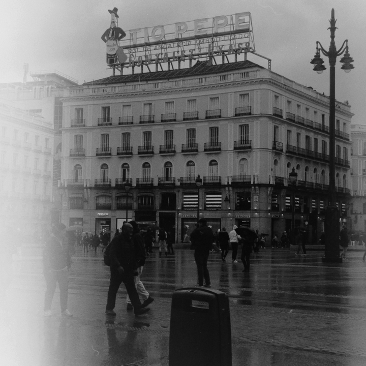 Rainy Day at Puerta del Sol with Iconic Tío Pepe Sign and Historic Architecture in Central Madrid (c) pmartinasi