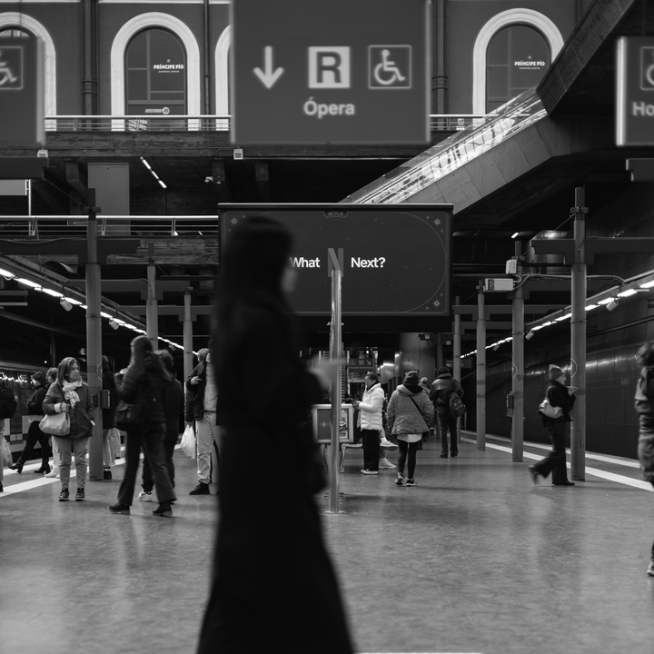 Candid black and white photograph captures a woman in motion blur walking across the platform at the busy Principe Pio Metro Station in Madrid, Spain, Europe. (c) pmartinasi